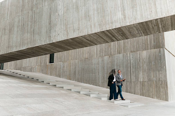istock Two mature businesspeople walking and talking in modern concrete building 2206881932