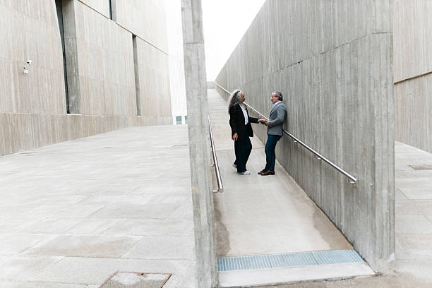istock Business partners shaking hands on a ramp outside modern building 2206882181