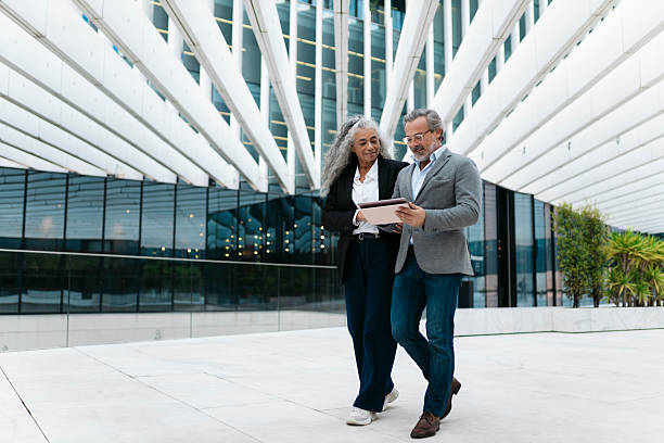 Senior business people walking and using digital tablet outside office