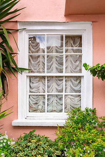 Charming white window on a pink wall with plants and curtains, located in dartmouth, devon, england