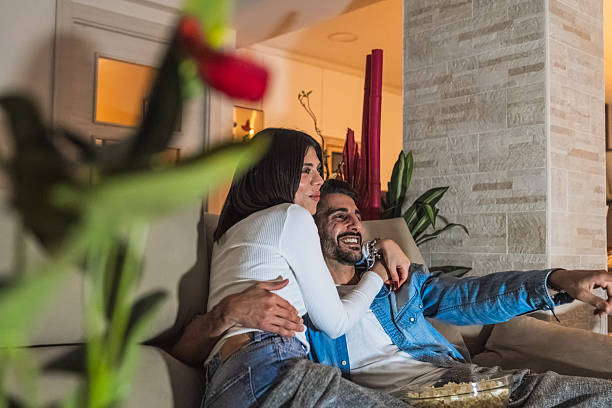 istock Young couple relaxing on sofa watching television at home 2206882631