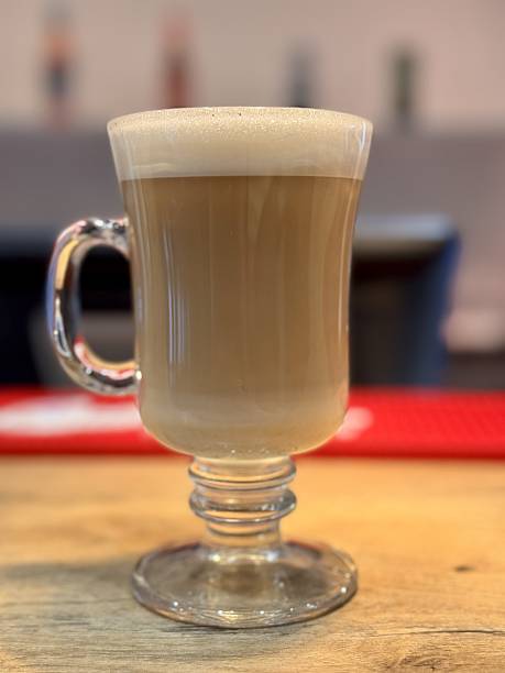 istock Savoring a Delicious Latte Crafted in a Clear Glass While Relaxing on a Wooden Table. A beautifully crafted latte served in a clear glass, presenting delicious layers of coffee and froth 2206883293