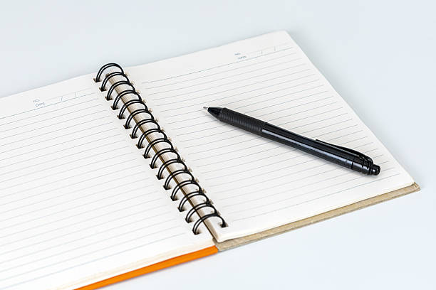 A sleek black pen lies on a fresh, open notebook.