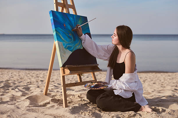 istock Young female painter creating beach art in peaceful setting 2206887400