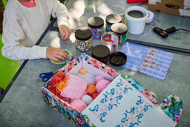 Child engaging in yarn crafts with colorful materials on table