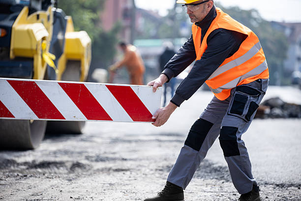 istock Construction worker sets up traffic barrier during road work in an urban area on a sunny day 2206888630