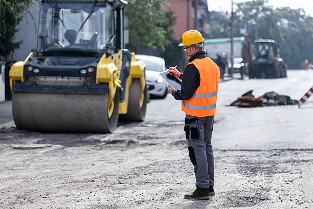 istock Construction worker conducts site inspection while monitoring roadwork with heavy machinery in urban area during daytime 2206888696