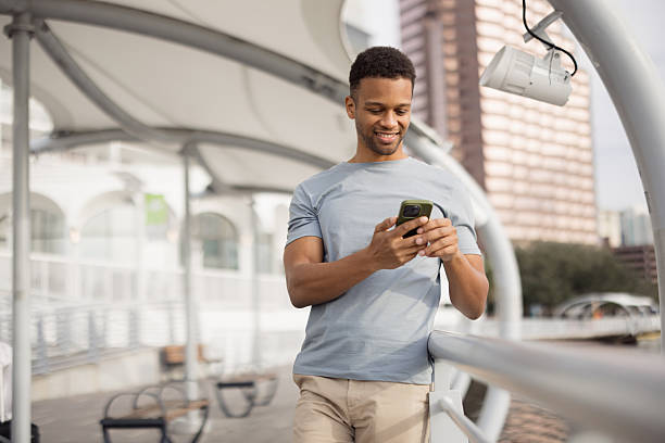 istock Young man enjoys using his phone in a modern city environment 2206889912