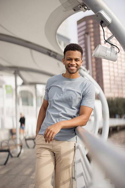 istock Young tourist smiling and leaning on railing in urban setting 2206889926