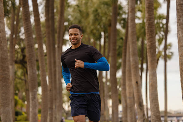 istock Young black man running in a park with palm trees 2206889955