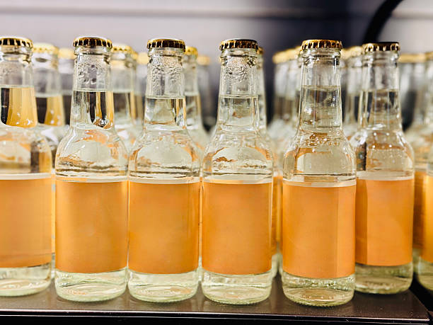 A symmetrical arrangement of bottled citrus drinks on display, highlighting the clear glass and golden caps.