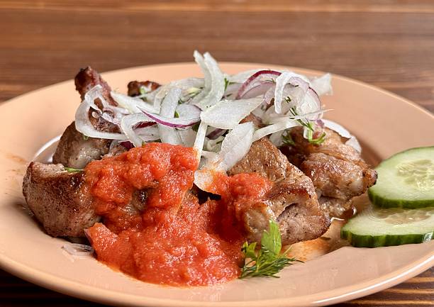 Savor the experience of Delicious Grilled Meat paired with Fresh Vegetables and flavorful Sauce. Enjoy grilled meat topped with crispy fried onions, rich tomato sauce, and crunchy cucumber slices on the side