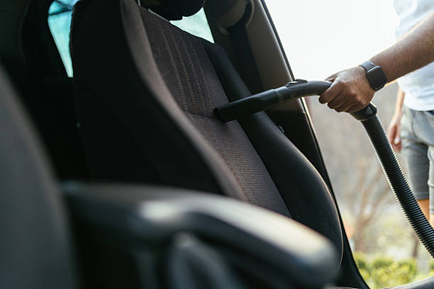 istock Man Vacuuming Car Seat Interior with Vacuum Cleaner in Sunlight 2206893660