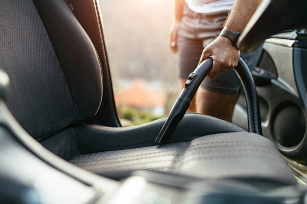 istock Man Vacuuming Car Seat Interior with Vacuum Cleaner in Sunlight 2206893670