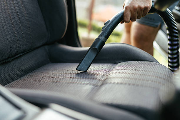 istock Man Vacuuming Car Seat Interior with Vacuum Cleaner in Sunlight 2206893685