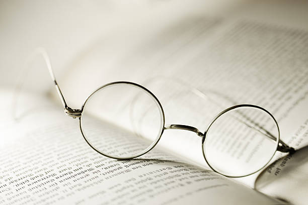 istock Vintage glasses on open antique book. Old round spectacles 2206896083