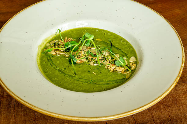 istock Green vegetable soup with microgreens and almond garnish in ceramic bowl 2206896501