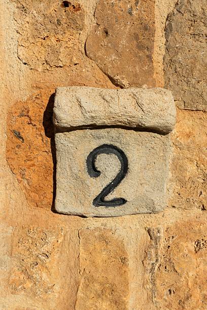 istock stone plaque number two 2 on sand colored stone wall close up 2206899324