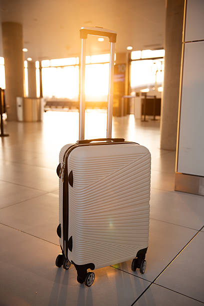 istock White suitcase stands in airport terminal at sunset 2206902277