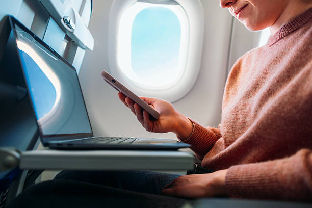 Business Traveler Using Smartphone and Laptop on Airplane Flight
