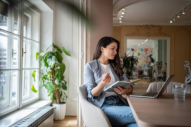 istock Businesswoman working from home taking notes while looking at laptop 2206914102