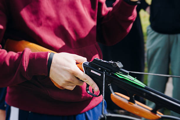 istock Crossbow shooting and archery at the shooting range, women and men practicing with arbalest at shooting gallery, compound bow training, aiming the target with arbalest at archery range, bow and arrows 2206917404