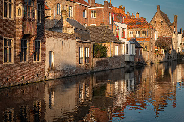 The serene canals of Bruges mirror the city's stunning historic architecture during the golden hour. A breathtaking spring evening in the heart of the old town, bathed in warm sunset hues