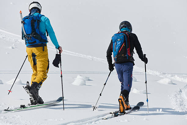 istock Alpine Ascent: Two Professional Skiers Conquer Snowy Peaks as a Determined Team. 2206922083