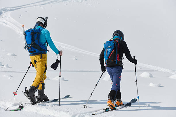 istock Alpine Ascent: Two Professional Skiers Conquer Snowy Peaks as a Determined Team. 2206925488