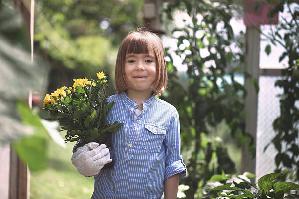 istock Smiling child holding chrysanthemum in pot 2206926893