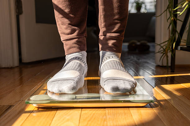 istock Male Stepping on Floor Scale - Weight Loss 2206927637