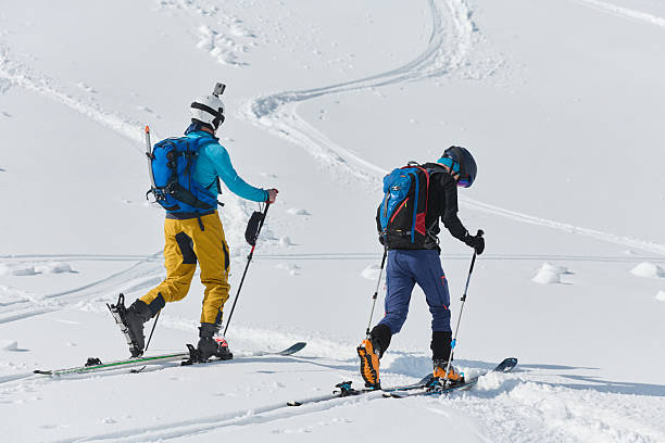 istock Alpine Ascent: Two Professional Skiers Conquer Snowy Peaks as a Determined Team. 2206930446
