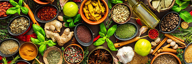 A visually striking arrangement of fresh spices and herbs on a brown surface, highlighting their vivid colors, intricate details and rich culinary essence, banner