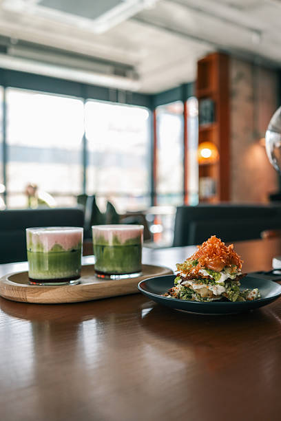 istock Close-up of a gourmet salad stack with creamy dressing and caramelized onions, served on a dark plate in a cozy modern cafÃ© setting with blurred background 2206931407