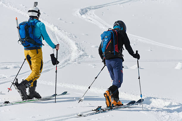 istock Alpine Ascent: Two Professional Skiers Conquer Snowy Peaks as a Determined Team. 2206932976