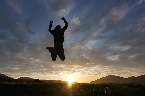 istock man jumping on the mountain with the sunset in the background 2206934116