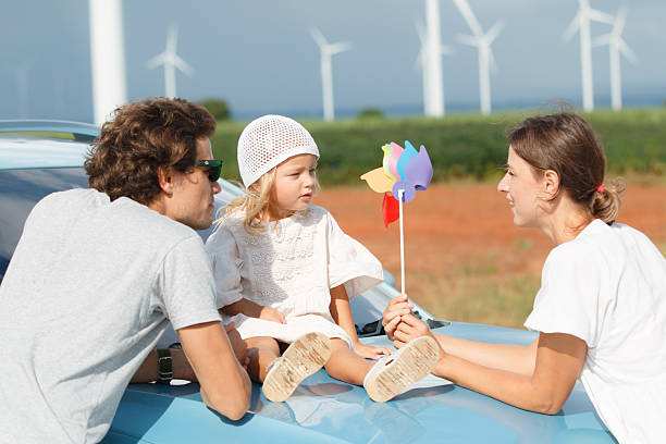 Happy cheerful caucasian white family with daughter are walking and relaxing together in the daytime in nature with windmill towers in background. Happy family activity concept.