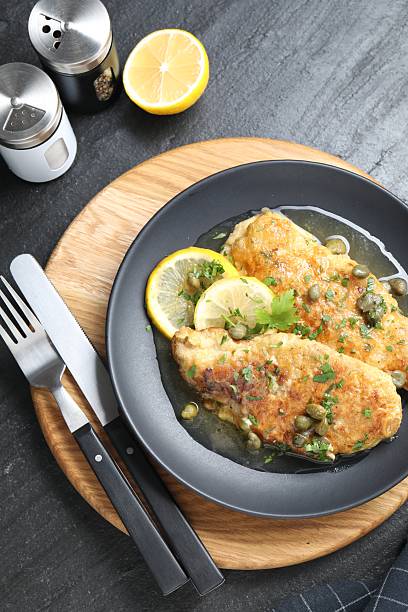 istock Delicious chicken piccata served on black table, flat lay 2206937779