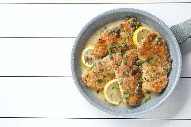 istock Delicious chicken piccata on white wooden table, top view. Space for text 2206939455