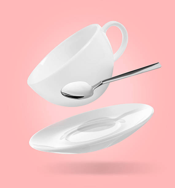 istock Spoon, cup and saucer falling on pink background 2206940556