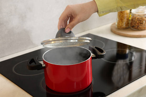 Woman's hand holding the lid of a pasta pot
