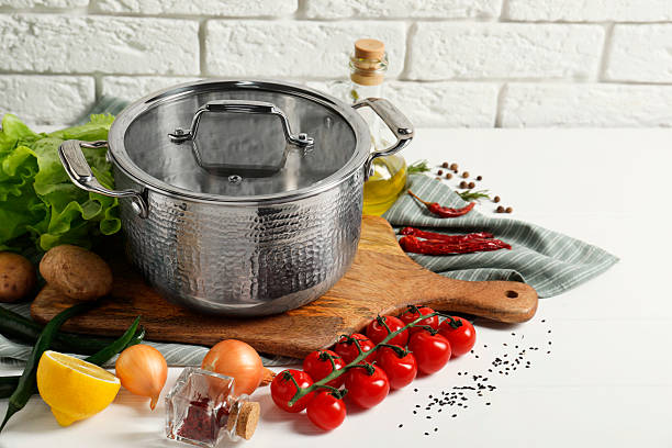 istock Cooking dinner. Pot, cutting board and different products on white table near brick wall, space for text 2206941584