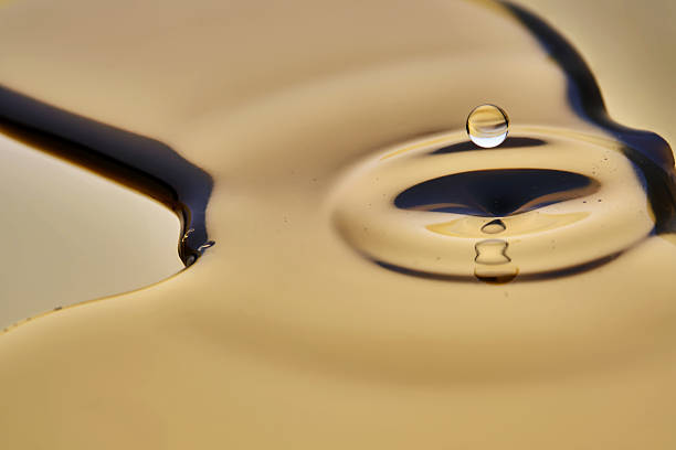 istock Texture of cosmetic oil with falling drop on golden background. 2206942684
