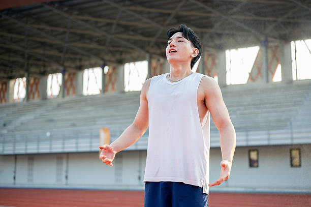 istock Asian man in white tank top standing with open arms and deep breathing, taking a rest after running. 2206946771