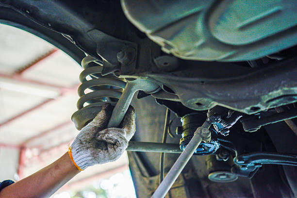 istock Mechanic adjusting car suspension system with wrench 2206947103