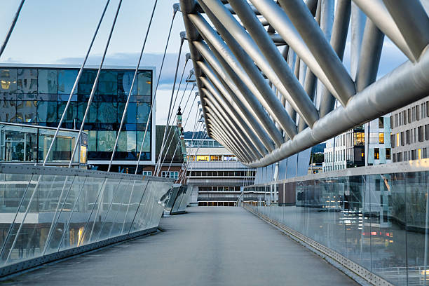 Oslo Pedestrian Bridge over Railway Tracks in the Capital City of Norway - Downtown Oslo. Modern Footbridge over tracks of Central Station. Modern Office buildings in the background. Vanishing Point of View along the Elevated Oslo Akrobaten Bru Pedestrian Footbridge. Oslo, Norway, Scandinavia, Northern Europe
