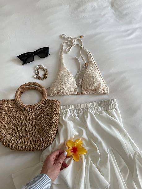 Woman arranging beachwear on bed before summer vacation