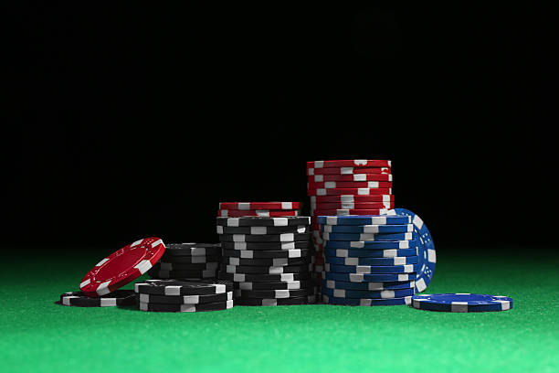 istock Poker chips on green table against dark background 2206950195
