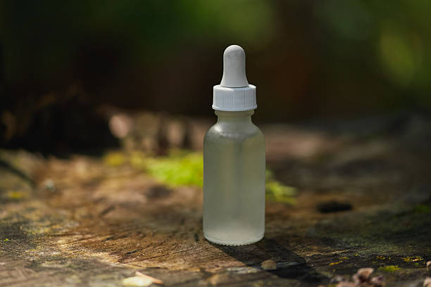istock Clear dropper bottle stands on a wooden surface surrounded by greenery 2206952965