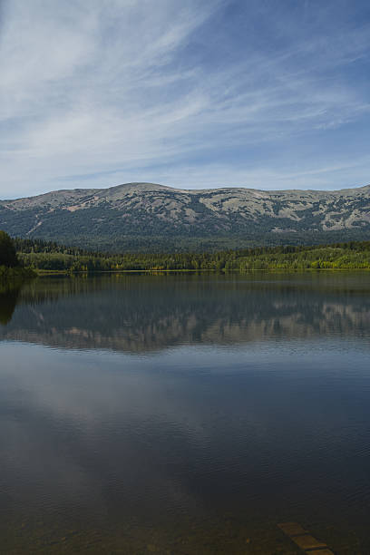 istock Calm lake reflecting mountains under a clear blue sky in a serene setting 2206952979